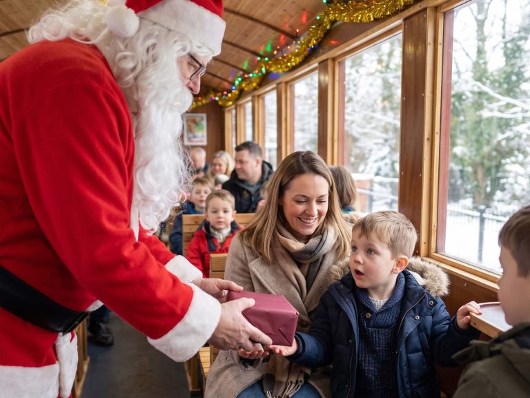 Santa hands a wrapped present to a young boy on board a Santa Special train in Leeds
